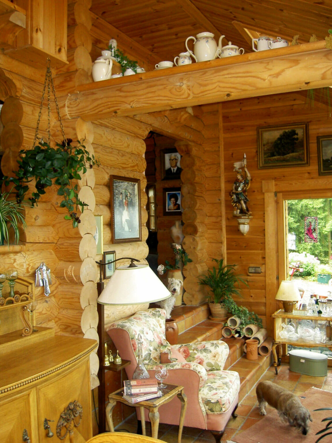 Innenraum eines traditionellen Holzblockhauses mit Holzmöbeln und natürlichem Licht, das die Holzoberflächen hervorhebt.